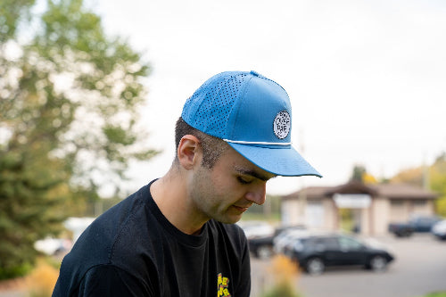 Male wearing light blue 19th Hole Rope Hat by Fore Over Par on a golf course