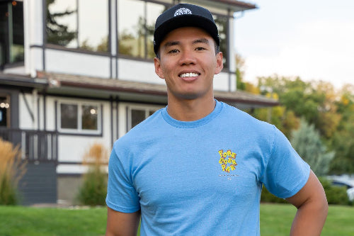 A 5'9" man on a golf course wearing a black 19th Hole Rope hat and medium light blue Fringe Society tee shirt by Fore Over Par