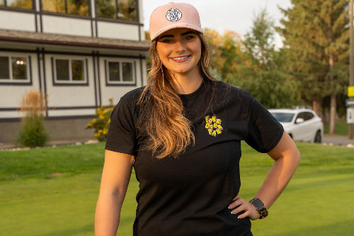 A 5'10" Woman on a golf course wearing a large black shirt and navy skirt, holding a golf club.