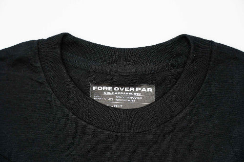 Close-up of a black crewneck t-shirt showing the inner neck label which reads 'FORE OVER PAR GOLF APPAREL,INC'.