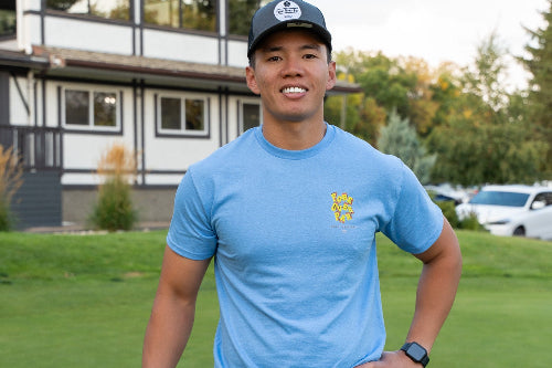 A 5'9" man on a golf course wearing a charcoal & black OG and Light Blue Fringe Society Tee Shirt by Fore Over Par