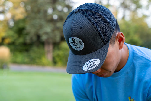 A man on a golf course wearing a charcoal and black OG Hat by Fore Over Par