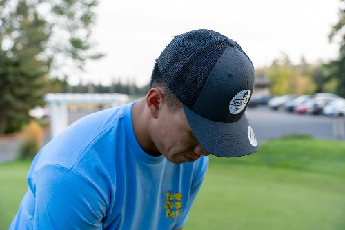 A man on a golf course wearing a charcoal and black OG hat by Fore Over Par