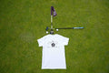 White T-shirt with large 'Fore Over Par' Logo on the back, shown on a golf green with purple flag, putter, and two golf balls behind it. 