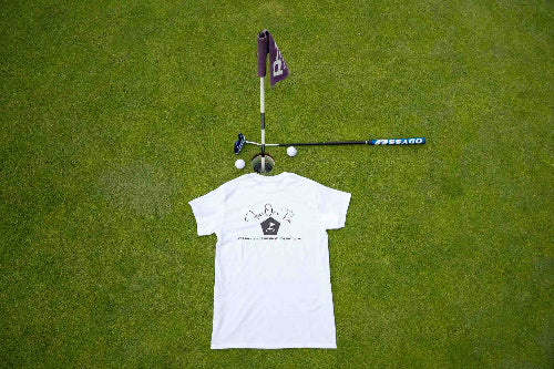 White T-shirt with large 'Fore Over Par' Logo on the back, shown on a golf green with purple flag, putter, and two golf balls behind it. 