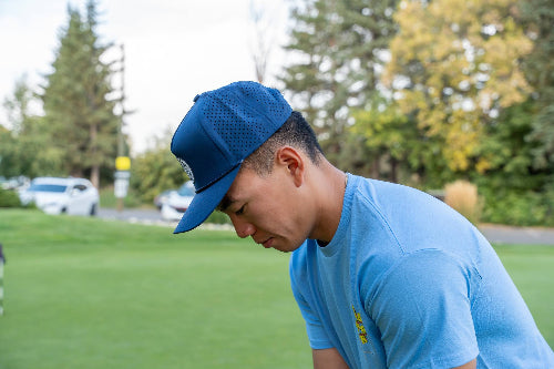 Male wearing dark blue 19th Hole Rope hat by Fore Over Par on golf course