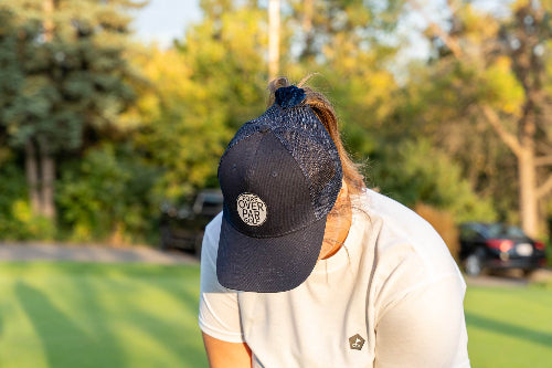 Female wearing a Dark Blue Pony Tail Club Hat by Fore Over Par while on a golf course. 