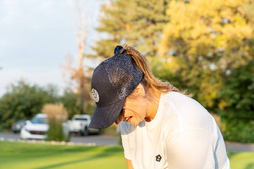 Female wearing a Dark Blue Pony Tail Club hat by Fore Over Par while on a golf course. 