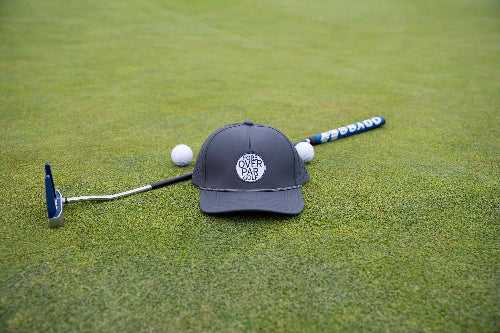 Dark Grey 19th Hole Rope Hat by Fore Over Par shown on golf green with putter and two golf balls behind it