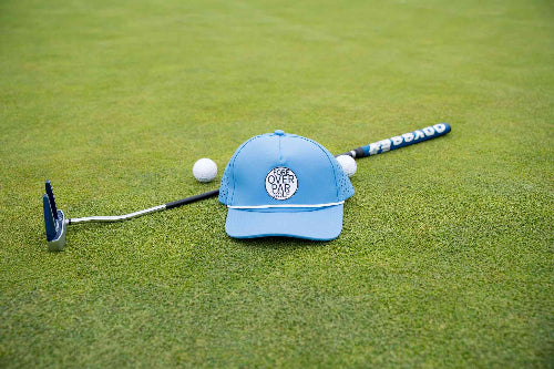 Light blue 19th Hole Rope Hat by Fore Over Par shown on a green with a putter and two golf balls behind it. 