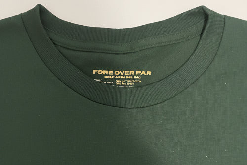 Close-up of a dark green crewneck t-shirt showing the inner neck label which reads 'FORE OVER PAR'.