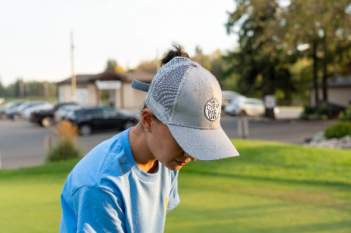 Female wearing a grey Pony Tail Club hat by Fore Over Par on a golf course. 