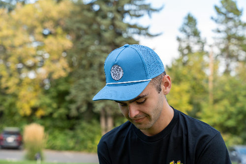 Male wearing a light blue 19th Hole Rope hat by Fore Over Par on a golf course