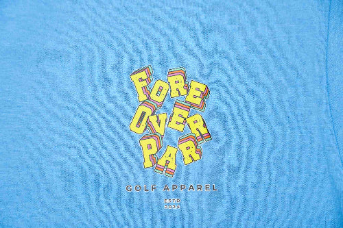 A close-up of a heather blue t-shirt featuring a retro-style graphic that reads 'FORE OVER PAR' in yellow letters with red and orange drop shadows, and 'GOLF APPAREL' printed below.