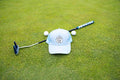 Light Blue Pony Tail Club hat by Fore Over Par shown on a golf green with a putter and two golf balls behind it. 