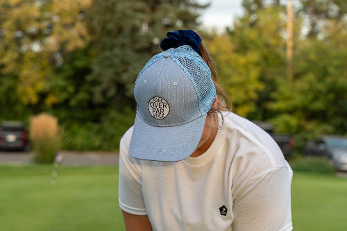 Female wearing a light blue Pony Tail Club hat by Fore Over Par on a golf course. 