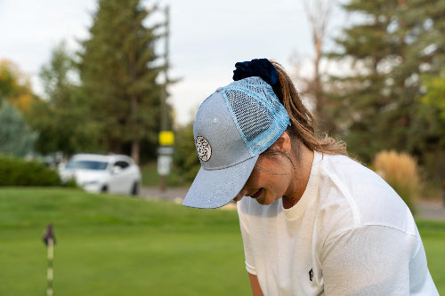 Female wearing a light blue Pony Tail Club hat by Fore Over Par on a golf course.