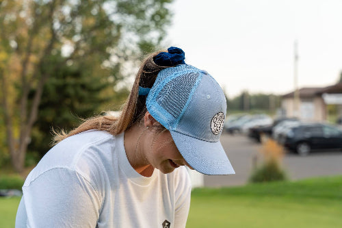 Female wearing a light blue Pony Tail Club hat by Fore Over Par on a golf course