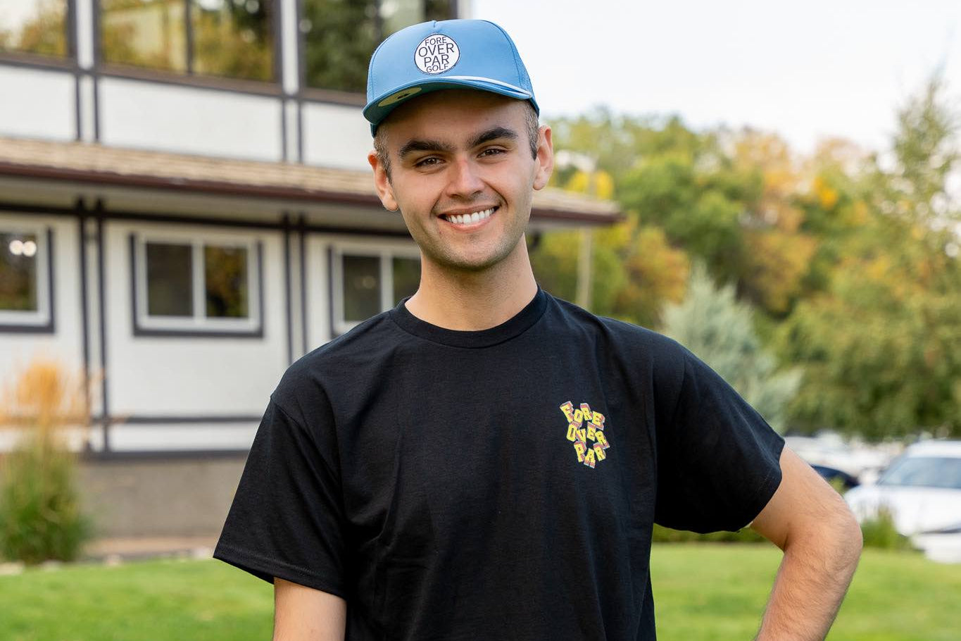 6'1" Male wearing a light blue 19th Hole Rope Hat and large black Fringe Society tee shirt by Fore Over Par on a golf course