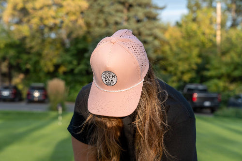 Woman wearing a pink 19th Hole Rope hat by Fore Over Par on a golf course. 