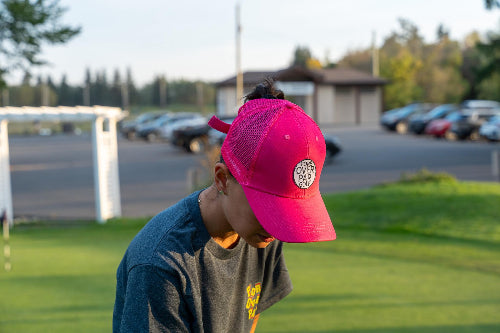 Female wearing a pink Pony Tail Club hat by Fore Over Par on a golf course