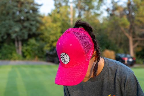 Female wearing a pink Pony Tail Club hat by Fore Over Par on a golf course
