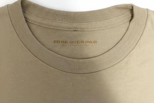 Close-up of a crewneck t-shirt in a sand colour, showing the inner neck label with the brand name 'FORE OVER PAR'.