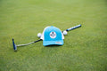 Turquoise & White OG Hat by Fore Over Par shown on golf green with a putter and two golf balls behind it.