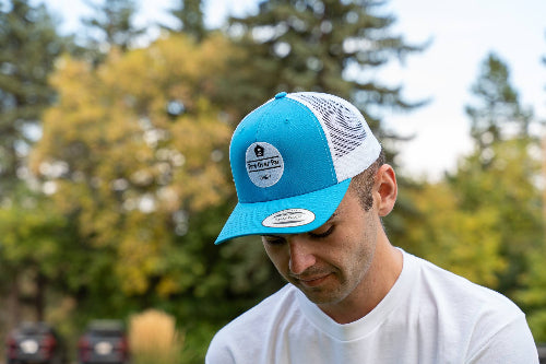 A man on a golf course wearing a turquoise & white OG Hat by Fore Over Par