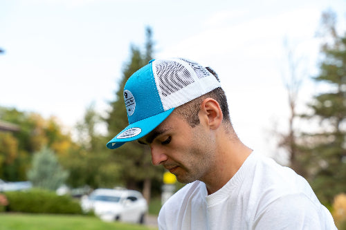 Man on a golf course wearing a turquoise & white OG hat by Fore Over Par.