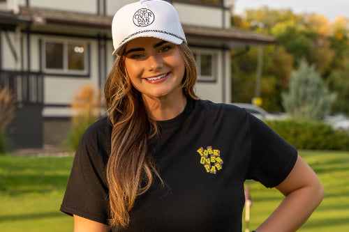 5'10" Woman wearing a 19th Hole Rope Hat and large black Fringe Society tee Shirt by Fore Over Par while on a golf course